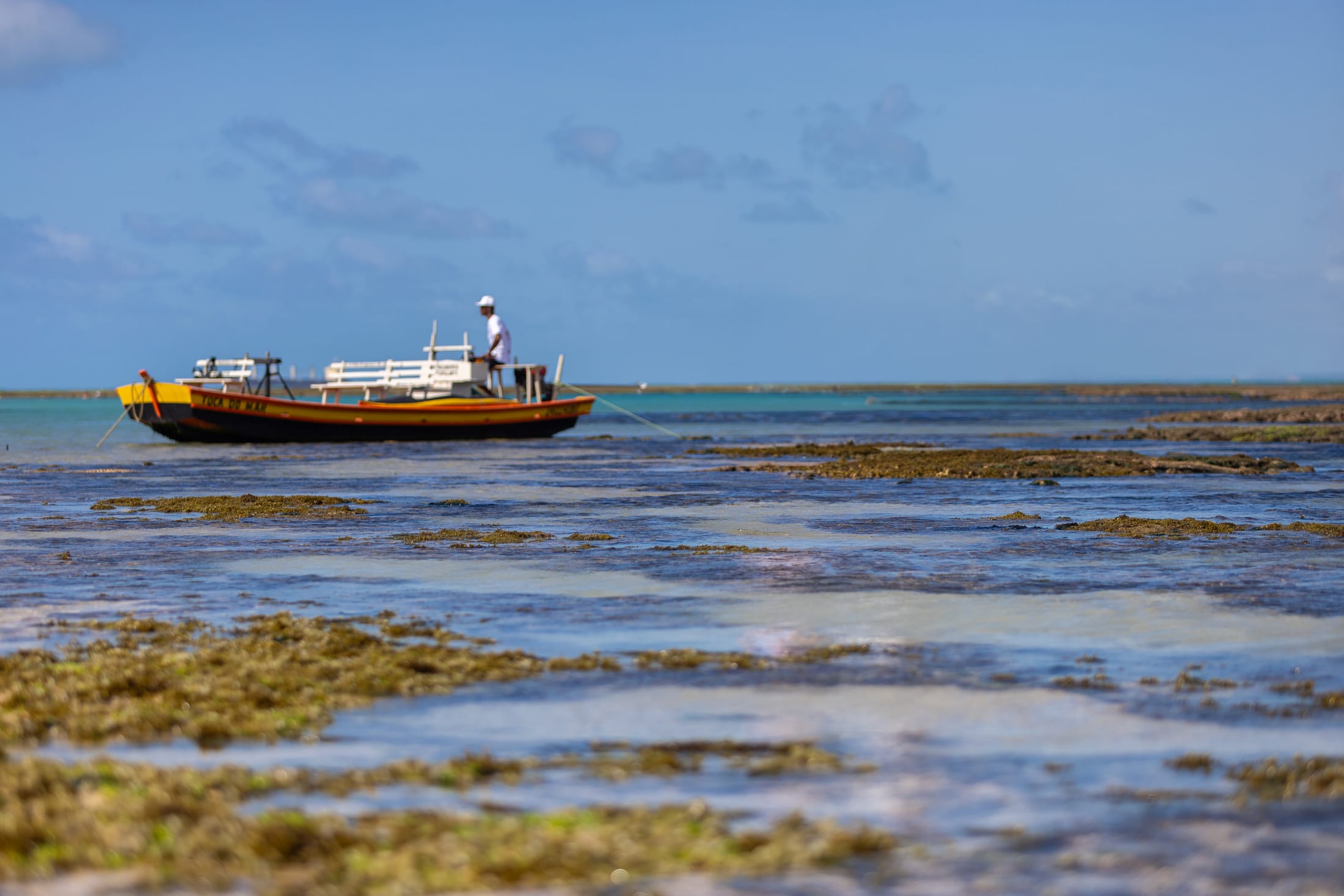 Piscina natural da Pajuçara com jangada e jangadeiro ao longe, em Maceió