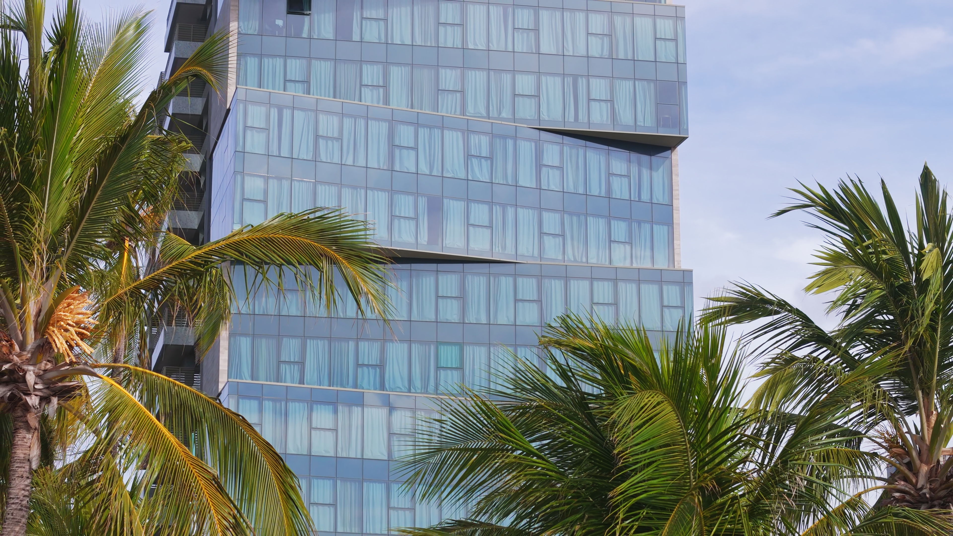 Fachada do Sais Beach Living Hotel com coqueiros à frente, em Maceió