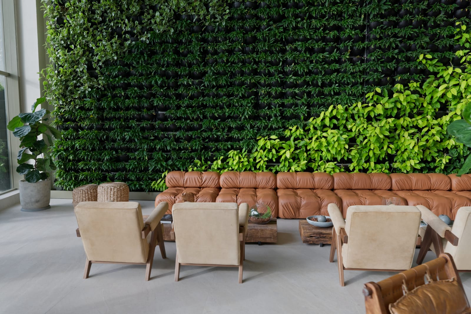 Sofá de couro e poltronas junto à parede de plantas do lobby